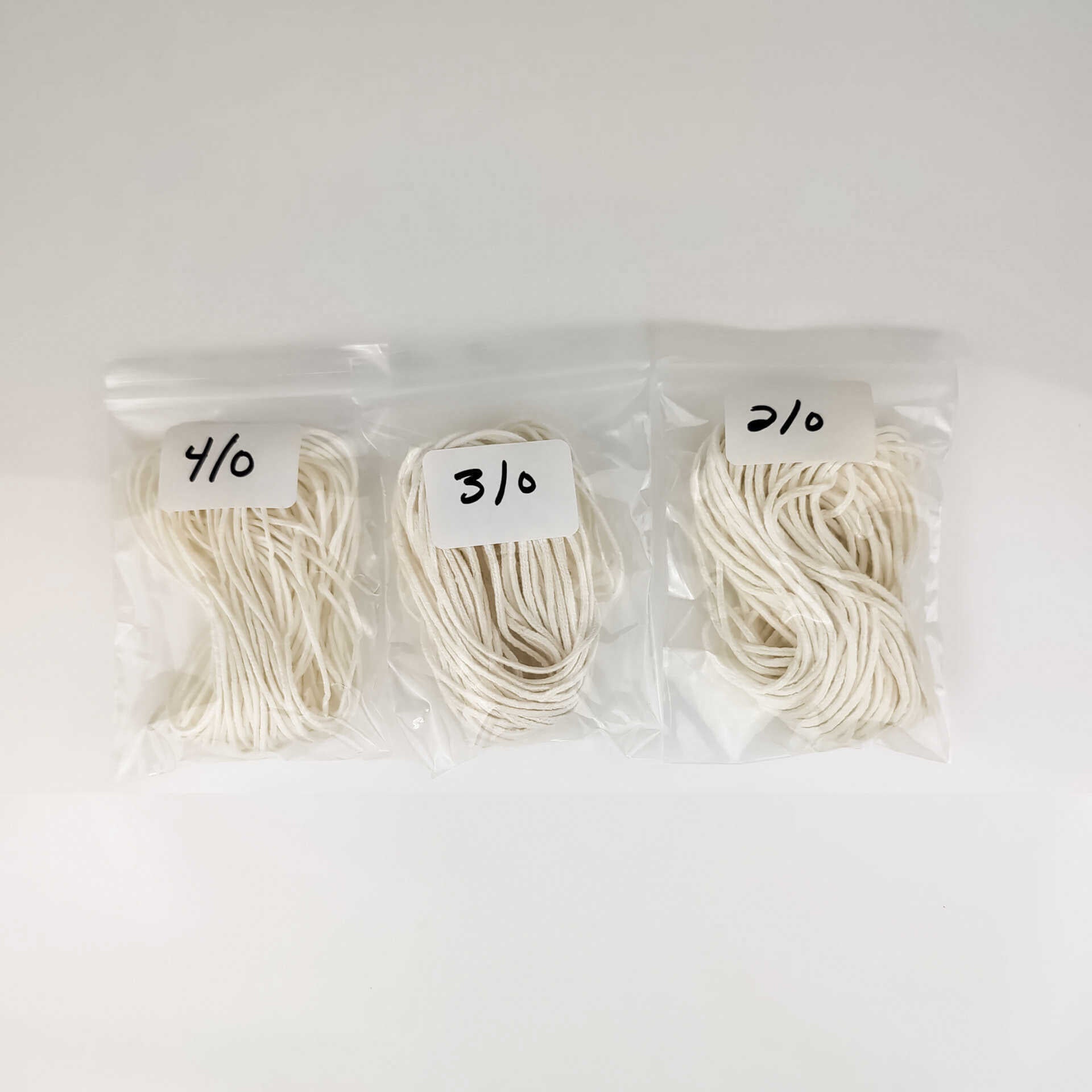 Three packages of white yarn with labels on a white background