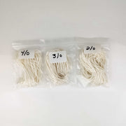 Three packages of white yarn with labels on a white background
